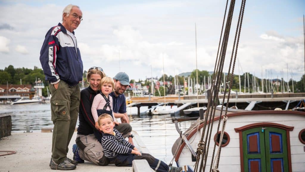 Familie på en brygge med båter og vann
