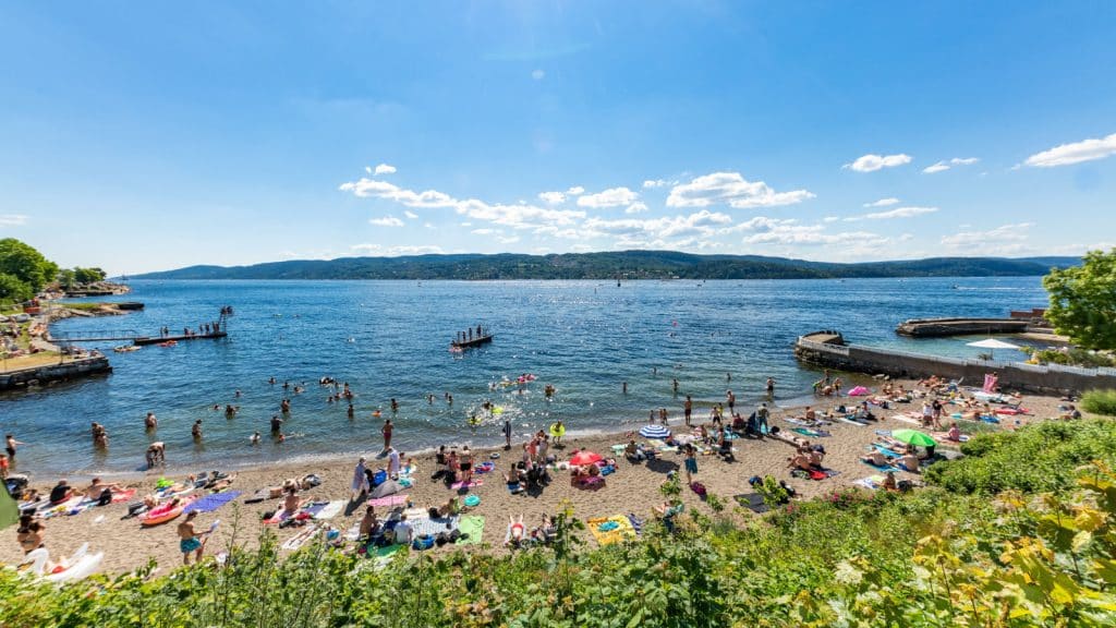 En folkerik strand langs fjorden
