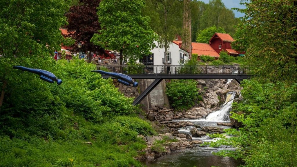 To blå dykkere henger over fossen på Bærums Verk som en del av kunstparken