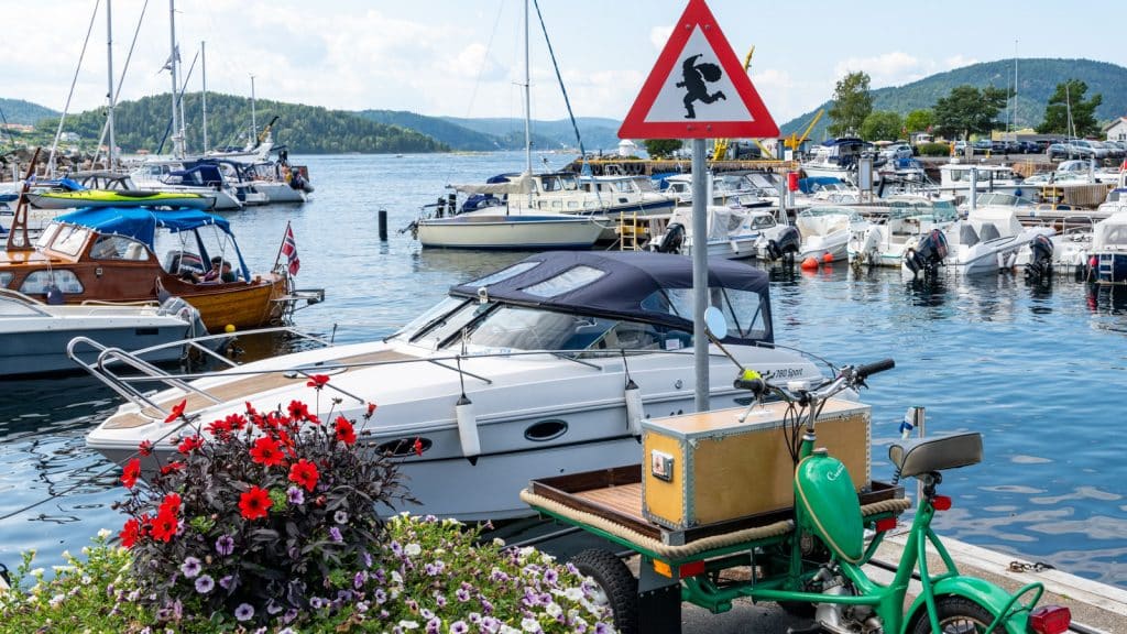 Fare for nisseskilt i en båthavn med båter og blomster