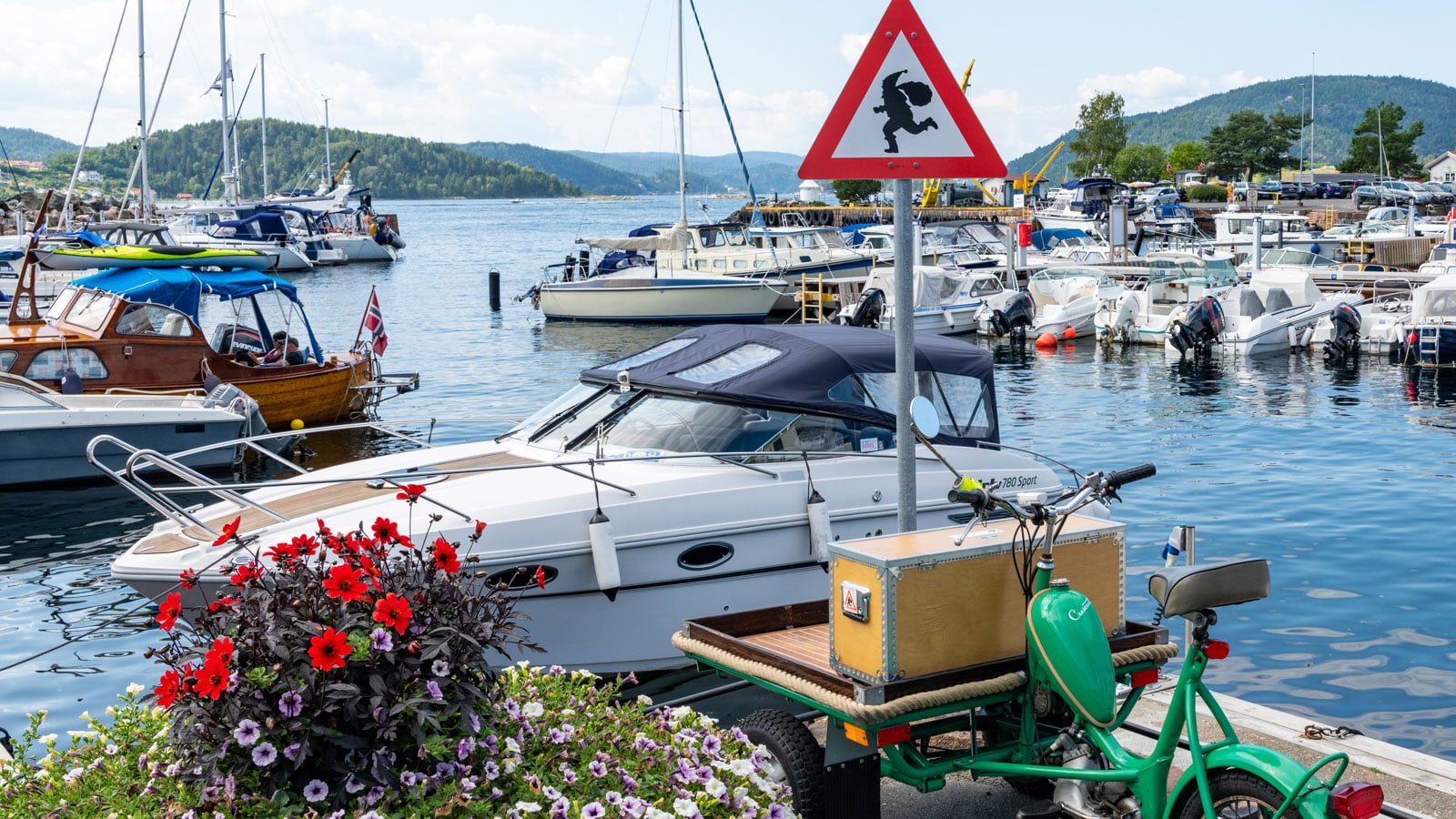 Fare for nisseskilt i en båthavn med båter og blomster