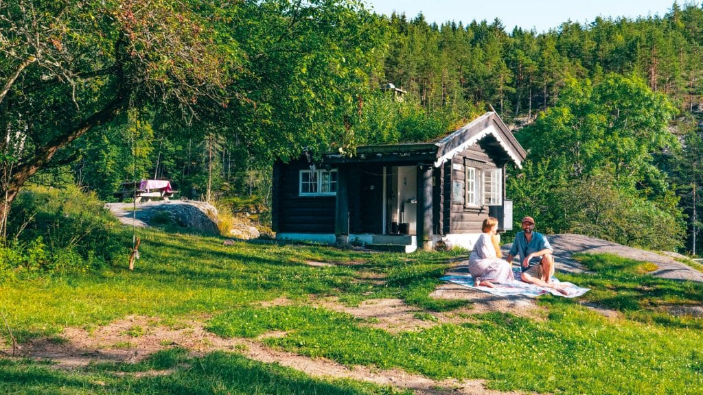Par som sitter utenfor en liten tømmerkoie på gressplen