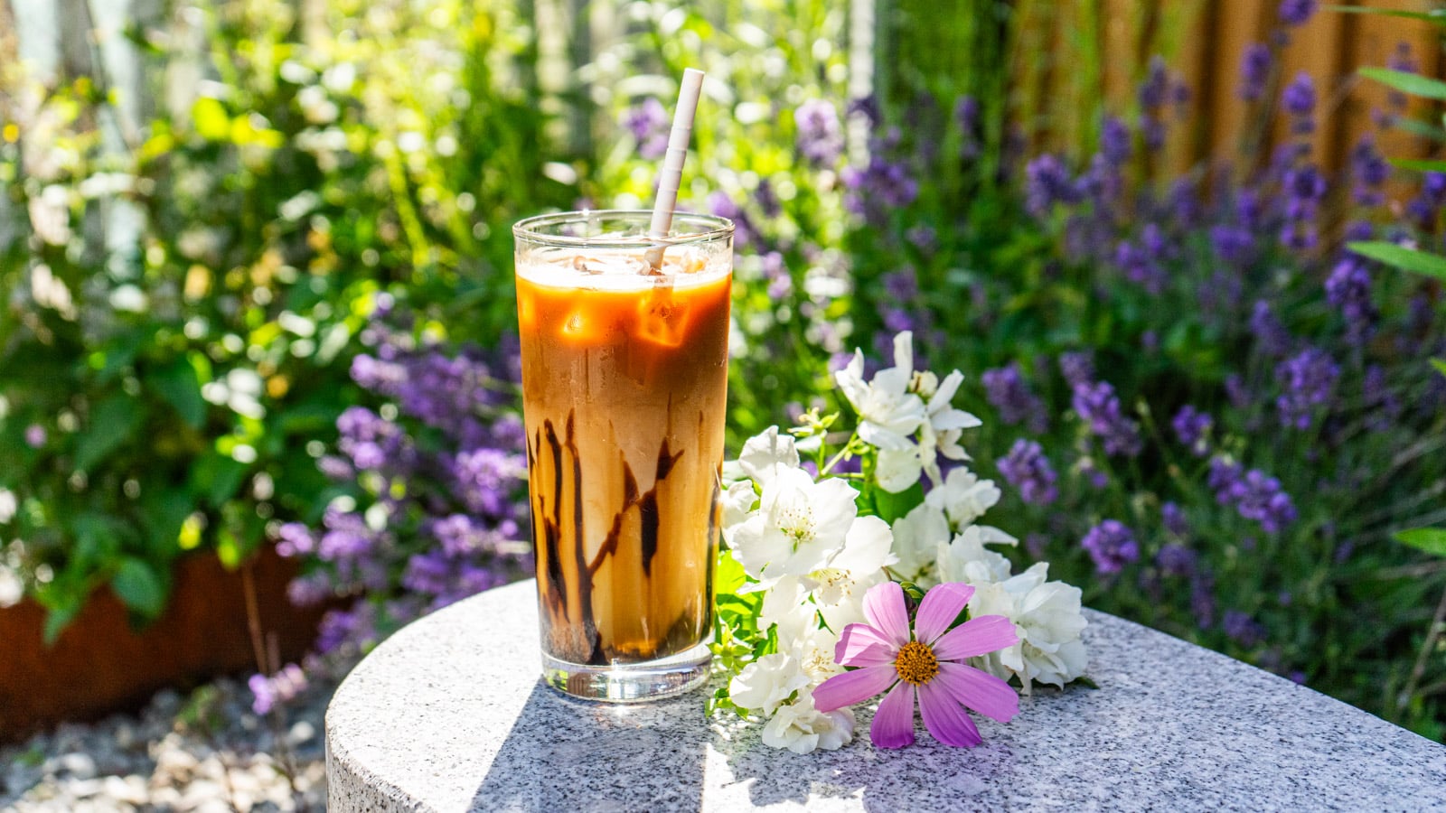 Iskaffe på et bord fult av sommerblomster