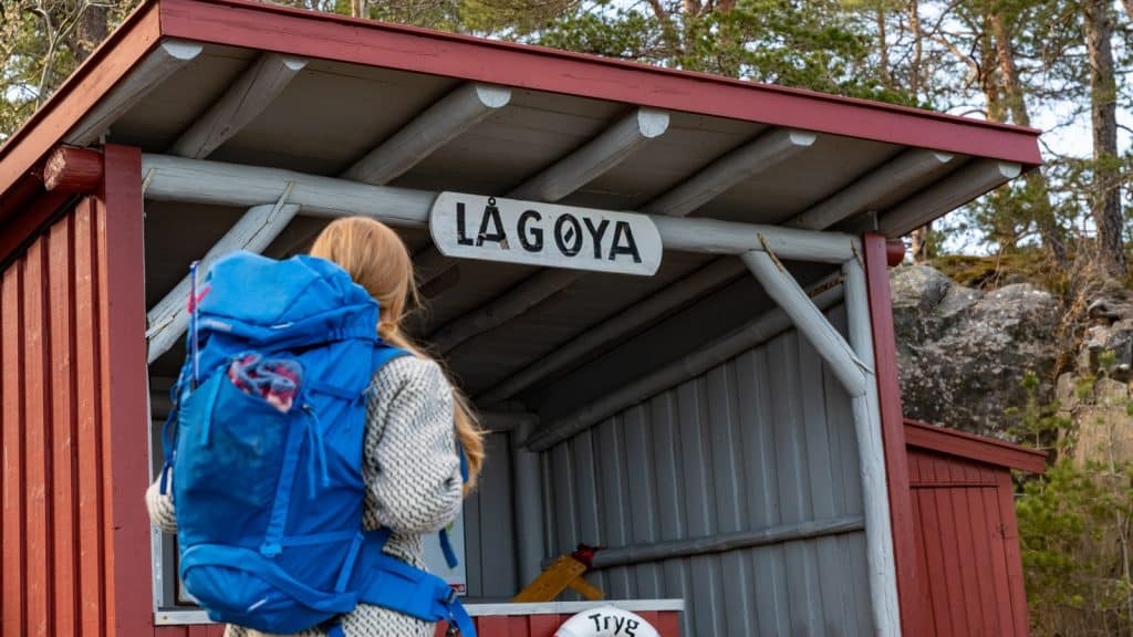 Jente med blå sekk som ser på et skilt av Lågøya
