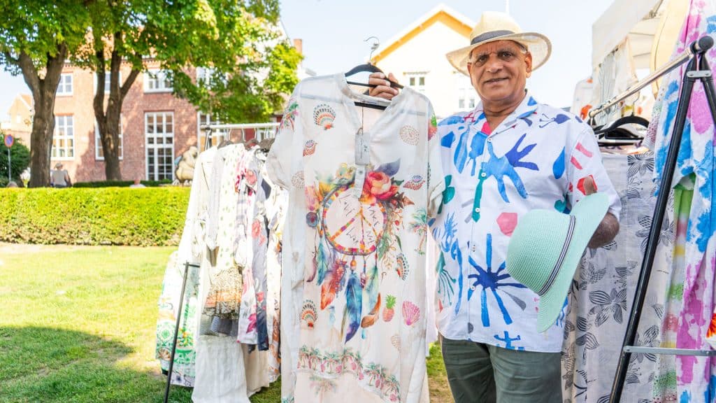 Mann som står med hatt og selger tunika på et torg om sommeren
