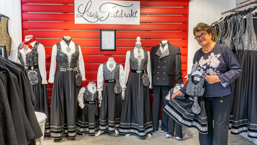 Dame som holder en festdrakt i en butikk med andre festdrakter