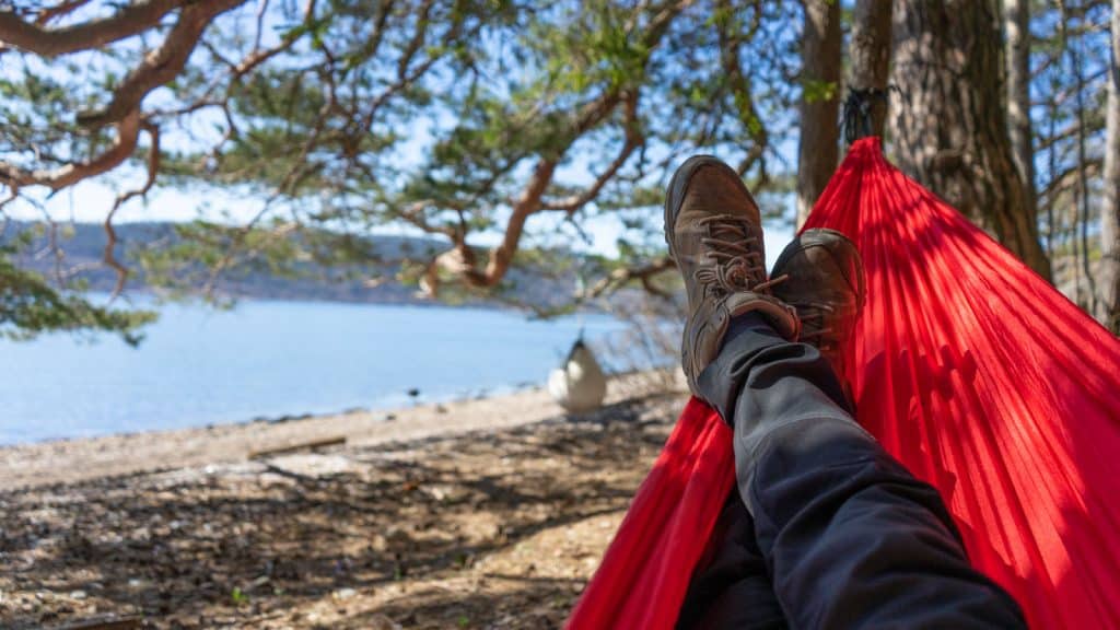 Sko som hviler i en rød hengekøye på en strand